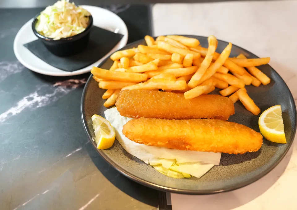 Two beer-battered cod fillets with fries, lemon and coleslaw